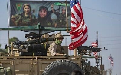 Un véhicule blindé armé passe à côté d'un panneau d'affichage pour les Unités de protections des femmes kurdes syriennes, lors d'une patrouille dans la ville du nord-est de la Syrie de Qahtaniyah à la frontière avec la Turquie, le 31 octobre 2019. (Photo par Delil SOULEIMAN / AFP)