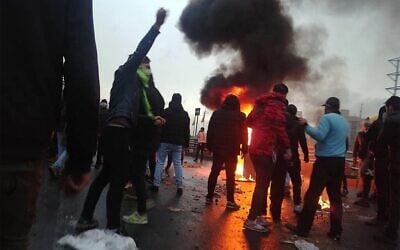 Des manifestants iraniens se rassemblent autour d'un feu lors d'une manifestation contre l'augmentation du prix de l'essence dans la capitale Téhéran, le 16 novembre 2019. (Crédit : AFP)