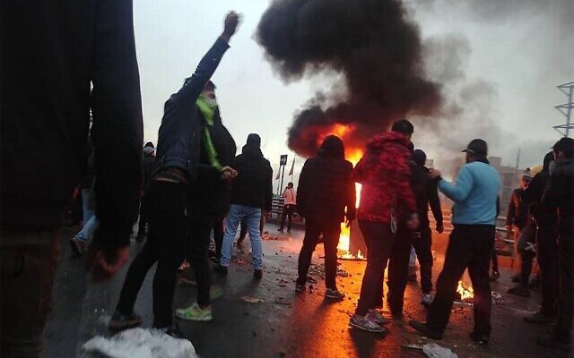 Des manifestants iraniens se rassemblent autour d'un feu lors d'une manifestation contre l'augmentation du prix de l'essence dans la capitale Téhéran, le 16 novembre 2019. (Crédit : AFP)