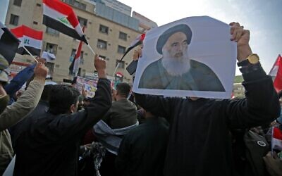 Des partisans irakiens du groupe armé Hashed Al-shaabi tiennent une photo de la plus haute autorité religieuse chiite du pays, l'Ayatollah Ali Sistani, alors qu'ils manifestent sur la place Tahrir de la capitale Baghdad, le 4 décembre 2019. 
(Photo par AHMAD AL-RUBAYE / AFP)