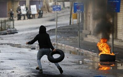 Un manifestant palestinien lance un pneu lors d'affrontements avec les forces de sécurité israéliennes dans la ville de Hébron, au sud de la Cisjordanie, le 9 décembre 2019, au milieu d'une grève générale contre les activités de construction israéliennes. (HAZEM BADER / AFP) Un manifestant palestinien lance un pneu lors d'affrontements avec les forces de sécurité israéliennes dans la ville de Hébron, au sud de la Cisjordanie, le 9 décembre 2019, au milieu d'une grève générale contre les activités de construction israéliennes. (HAZEM BADER / AFP)