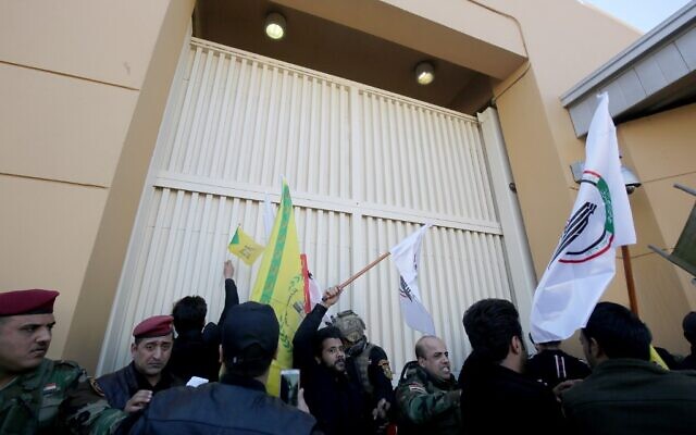 Des membres des forces de sécurité irakiennes tentent d'éloigner les manifestants d'une des portes de l'ambassade américaine après avoir franchi le mur extérieur de la mission diplomatique à Bagdad lors d'une manifestation de colère le 31 décembre 2019 pour dénoncer les frappes aériennes américaines du week-end qui ont tué des individus issus de groupes soutenus par l'Iran en Irak. (Crédit : AHMAD AL-RUBAYE / AFP)