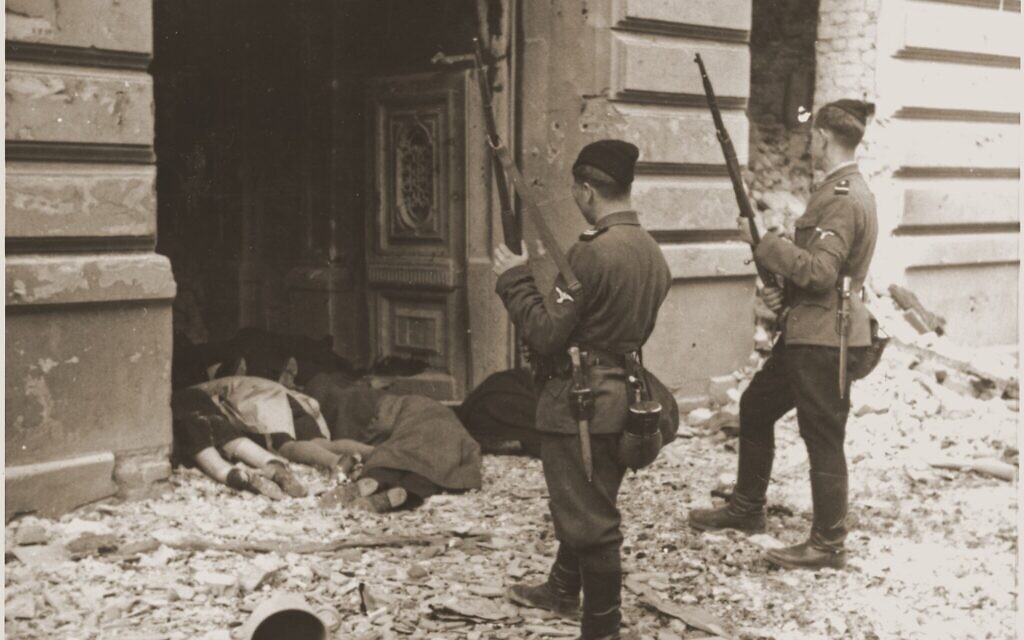 Des gardes Askari ou Trawniki regardent par une porte les corps des Juifs tués pendant la répression du soulèvement dans le ghetto de Varsovie. (Crédit : musée de la Shoah de Washington) Des gardes Askari ou Trawniki regardent par une porte les corps des Juifs tués pendant la répression du soulèvement dans le ghetto de Varsovie. (Crédit : musée de la Shoah de Washington)