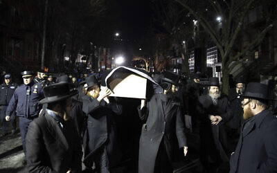 Des juifs orthodoxes portent le cercueil avec Mindel Ferencz devant une synagogue de Brooklyn, le mercredi 11 décembre 2019, à New York. Ses funérailles auront lieu à Jersey City. Ferencz a été tué mardi lors de la fusillade dans son épicerie casher de Jersey City. (Crédit : AP Photo/Mark Lennihan)