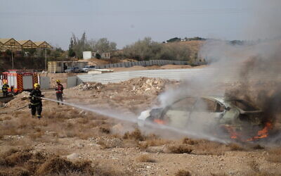 Des pompiers éteignent un incendie dans une voiture lors d'un exercice de l'armée israélienne simulant une attaque à la roquette dans l'implantation de Kfar Adumim, en Cisjordanie, le 11 décembre 2019. (Crédit ; Judah Ari Gross/The Times of Israel)