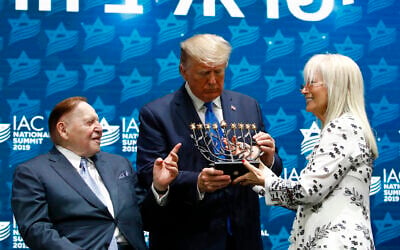 Le président Donald Trump reçoit une ménorah du directeur général de la Las Vegas Sands Corporation et grand donateur républicain Sheldon Adelson, à gauche, et de son épouse Miriam Adelson au sommet national du Conseil américain israélien à Hollywood, en Floride, le samedi 7 décembre 2019. (Crédit : AP Photo/Patrick Semansky)