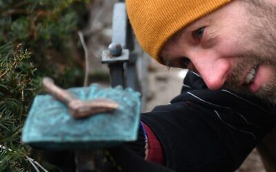 Le sculpteur Mihajlo (Mihaly) Kolodko et sa nouvelle sculpture de petite taille, la « hache », à proximité du monument soviétique de la Seconde Guerre mondiale sur la place de la Liberté à Budapest, en Hongrie, le 3 janvier 2020. (Crédit : Attila KISBENEDEK / AFP)