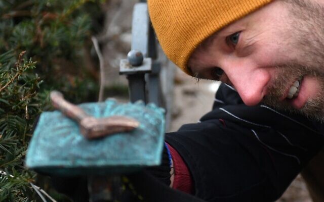 Le sculpteur Mihajlo (Mihaly) Kolodko et sa nouvelle sculpture de petite taille, la « hache », à proximité du monument soviétique de la Seconde Guerre mondiale sur la place de la Liberté à Budapest, en Hongrie, le 3 janvier 2020. (Crédit : Attila KISBENEDEK / AFP)