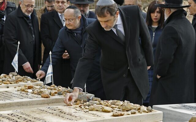 Le ministre français de l'Intérieur Christophe Castaner se rend sur les tombes des victimes de l'attentat de l'école Ozar Hatorah à Toulouse, au cimetière israélien de Givat Shaul à Jérusalem, le 23 janvier 2020. En arrière plan, Eva Sandler, qui a parti son mari et ses deux fils Aryeh et Gabriel lors de cette tuerie antisémite. (Crédit : JACK GUEZ / AFP) Le ministre français de l'Intérieur Christophe Castaner se rend sur les tombes des victimes de l'attentat de l'école Ozar Hatorah à Toulouse, au cimetière israélien de Givat Shaul à Jérusalem, le 23 janvier 2020. En arrière plan, Eva Sandler, qui a parti son mari et ses deux fils Aryeh et Gabriel lors de cette tuerie antisémite. (Crédit : JACK GUEZ / AFP)
