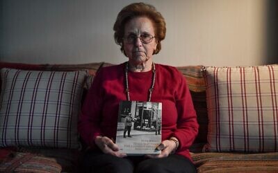 Nina Camhi, âgée de 80 ans, tient un livre sur la "Shoah des Juifs grecs" montrant la librairie de son grand-mère à Thessalonique, dans sa maison à Athènes, le 20 janvier 2020. (Photo par LOUISA GOULIAMAKI / AFP)