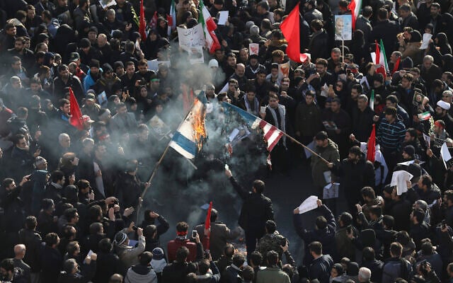 Des personnes en deuil brûlent les drapeaux des États-Unis et d'Israël lors d'une cérémonie funéraire sur la place Enqelab-e-Eslami (Révolution islamique) à Téhéran, en Iran, le 6 janvier 2020, pour le général iranien Qassem Soleimani et ses frères de combat, tués en Irak dans une frappe de drones américains vendredi. (Crédit : AP Photo / Ebrahim Noroozi)