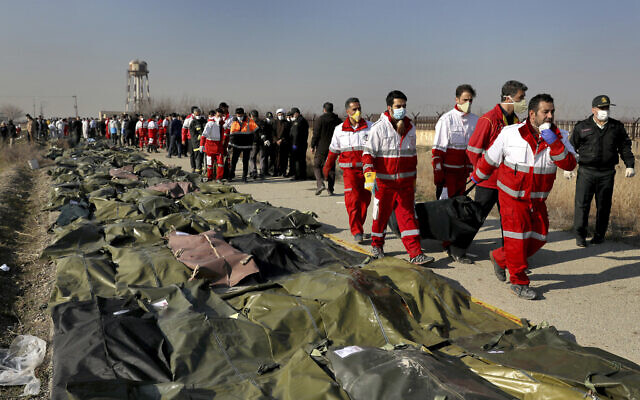 Des secouristes portent le corps d'une victime suite au crash d’un avion ukrainien à Shahedshahr, au sud-ouest de Téhéran, en Iran, le 8 janvier 2020 (Crédit : AP / Ebrahim Noroozi)