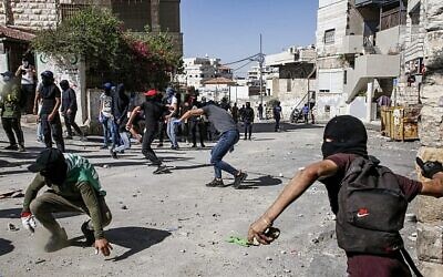 Des Palestiniens jettent des pierres lors d'affrontements avec la police israélienne dans le quartier d'Issawiya à Jérusalem le 28 juin 2019, un jour après qu'un Palestinien a été tué par balle par la police lors d'une manifestation dans le même quartier. (Crédit : Hazem Bader/AFP) Des Palestiniens jettent des pierres lors d'affrontements avec la police israélienne dans le quartier d'Issawiya à Jérusalem le 28 juin 2019, un jour après qu'un Palestinien a été tué par balle par la police lors d'une manifestation dans le même quartier. (Crédit : Hazem Bader/AFP)
