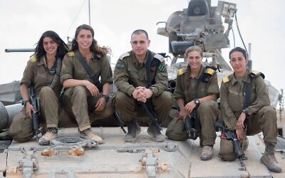 Le chef de forces blindés de l'armée israélienne, le général Guy Hasson, au centre, prend la pose sur un tank avec la première femme commandant de l'armée, qui a terminé sa formation , le 28 juin 2018. (Tsahal)