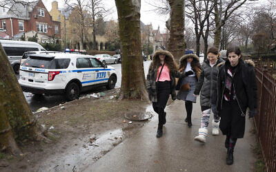 Des jeunes filles juives passent à côté d'une voiture de police garée dans le quartier de 
Crown Heights le lundi 30 décembre  2019 dans le district de Brooklyn à New York. (AP Photo/Mark Lennihan)