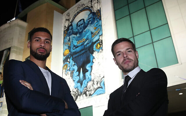 Les footballeurs de Chelsea Cesar Azpilicueta, (à droite), et Ruben Loftus-Cheek se tiennent devant la fresque du club commémorant les victimes de la Shoah à Londres, le 15 janvier 2020. (Avec l'aimable autorisation du Chelsea FC via la JTA)