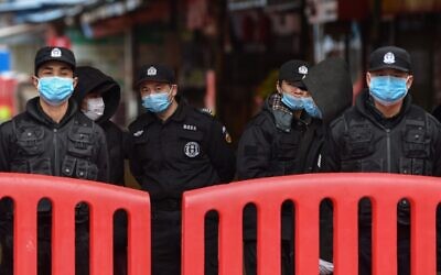 Des officiers de police et des gardes de sécurité montent la garde devant le Marché de fruits de mer d'Huanan où le coronavirus a été détecté à Wuhan, le 24 janvier 2020. (Photo par Hector RETAMAL / AFP) Des officiers de police et des gardes de sécurité montent la garde devant le Marché de fruits de mer d'Huanan où le coronavirus a été détecté à Wuhan, le 24 janvier 2020. (Photo par Hector RETAMAL / AFP)