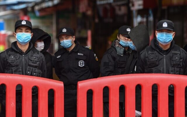Des officiers de police et des gardes de sécurité montent la garde devant le Marché de fruits de mer d'Huanan où le coronavirus a été détecté à Wuhan, le 24 janvier 2020. (Photo par Hector RETAMAL / AFP)
