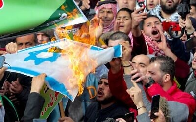 Des Jordaniens et des Palestiniens brûlent un drapeau israélien alors qu'ils participent à une manifestation à Amman, devant la mosquée al-Husseini au centre de la capitale, pour protester contre la proposition de paix présentée par les Etats-Unis pour le Moyen Orient, le 31 janvier 2020. (Crédit : Khalil MAZRAAWI / AFP)