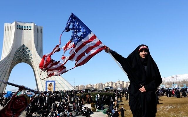 Une femme iranienne brandit un drapeau américain brûlé lors des commémorations marquant les 41 ans de la Révolution islamique sur la place Azadi, à Téhéran, le 11 février 2020. (Crédit : Atta KENARE / AFP)