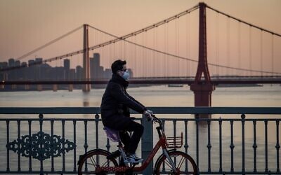 Un homme portant un masque de protection à vélo à Wuhan, dans la province centrale de Hubei, en Chine, le 17 février 2020. (Crédit : STR / AFP ) Un homme portant un masque de protection à vélo à Wuhan, dans la province centrale de Hubei, en Chine, le 17 février 2020. (Crédit : STR / AFP )