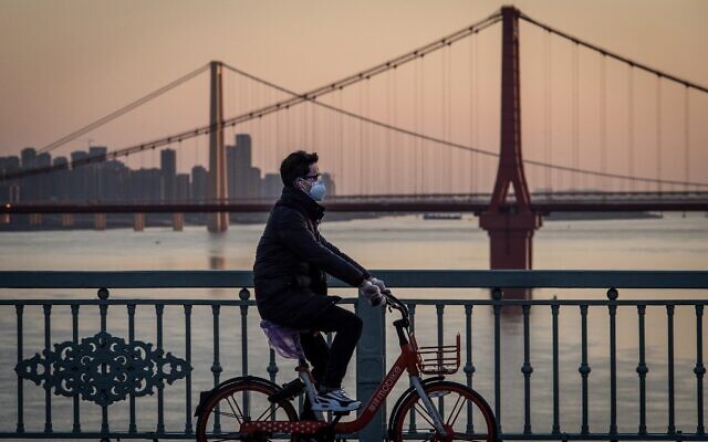 Un homme portant un masque de protection à vélo à Wuhan, dans la province centrale de Hubei, en Chine, le 17 février 2020. (Crédit :  STR / AFP )