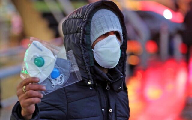 Un vendeur de rue iranien propose des masques de protection à Téhéran, le 20 décrier 2020. (Crédit : ATTA KENARE / AFP)