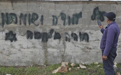 Un homme prend en photo un slogan anti-arabe tagué en hébreu "il y aura une guerre en Judée et Samarie" dans le village cisjordanien de Yasuf, à proximité de Naplouse, le 26 février 2020. (Photo par JAAFAR ASHTIYEH / AFP)