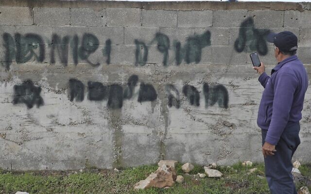 Un homme prend en photo un slogan anti-arabe tagué en hébreu "il y aura une guerre en Judée et Samarie" dans le village cisjordanien de Yasuf, à proximité de Naplouse, le 26 février 2020. (Photo par JAAFAR ASHTIYEH / AFP)