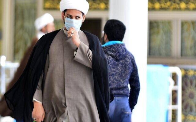 Un religieux irakien portant un masque de protection passe dans la ville sainte centrale de Najaf, le 26 février 2020. (Crédit : Haidar HAMDANI / AFP)