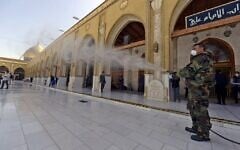 Un membre de la défense civile irakienne pulvérise du désinfectant sur et autour de la Grande Mosquée de Kufa, à 10 kilomètres au nord-est de la ville sanctuaire de Najaf dans le centre de l'Irak, le 27 février 2020. (Crédit : Haidar HAMDANI / AFP)