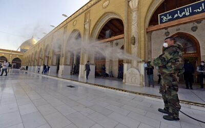 Un membre de la défense civile irakienne pulvérise du désinfectant sur et autour de la Grande Mosquée de Kufa, à 10 kilomètres au nord-est de la ville sanctuaire de Najaf dans le centre de l'Irak, le 27 février 2020. (Crédit : Haidar HAMDANI / AFP)