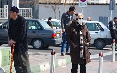 Une Iranienne portant un masque de protection et des gants, dans une rue animée de la capitale Téhéran, le 22 février 2020. (Crédit : ATTA KENARE / AFP)