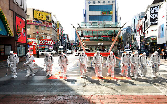 Des soldats de l'armée sud-coréenne portant des combinaisons de protection pulvérisent du désinfectant pour empêcher la propagation du virus COVID-19 dans une rue de Daegu, en Corée du Sud, le 27 février 2020 (Crédit : Lee Moo-ryul/Newsis via AP)