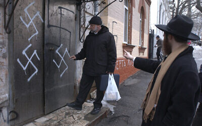 Illustration :le chef de la communauté juive Gennady Klebanov, à gauche, est sur le point d'entrer par la porte de la synagogue taguée de croix gammées, que le rabbin en chef de Vladivostok Isroel Silberstain, à droite, montre du doit, au port russe d'Extrême-Orient de Vladivostok, le 2 mars 2007. (Crédit : AP)