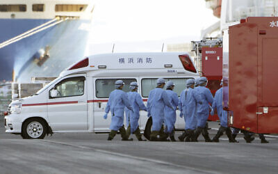Les membres des forces d'auto-défense japonaises marchent vers le navire de croisière Diamond Princess mis en quarantaine sur le port de Yokohama au Japon, le 9 février 2020 (Crédit :  AP Photo/Eugene Hoshiko)