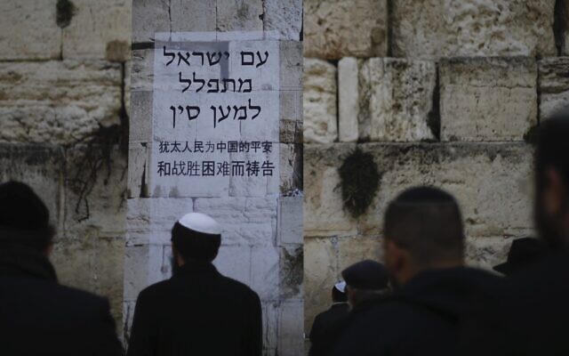 Des Juifs prient au mur Occidental, dans la Vieille Ville de Jérusalem, lors d'une prière pour les malades du coronavirus apparu en Chine. L'affiche dit "Le peuple d'Israël prie pour la Chine". Photo prise le 16 février 2020 (Crédit : Ariel Schalit/AP) Des Juifs prient au mur Occidental, dans la Vieille Ville de Jérusalem, lors d'une prière pour les malades du coronavirus apparu en Chine. L'affiche dit "Le peuple d'Israël prie pour la Chine". Photo prise le 16 février 2020 (Crédit : Ariel Schalit/AP)
