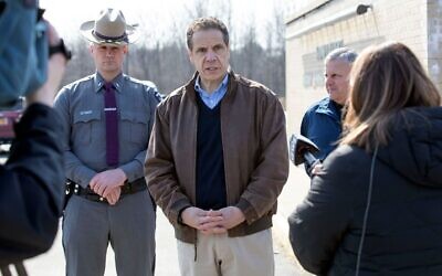 Le gouverneur de New York Andrew Cuomo, au centre, s'entretient avec des journalistes devant le centre communautaire juif Sidney Albert Albany après que le bâtiment a été évacué en raison d'une menace à la bombe envoyée par e-mail, le 24 février 2020. (Crédit : Mike Groll/Bureau du gouvernement Andrew Cuomo via JTA)