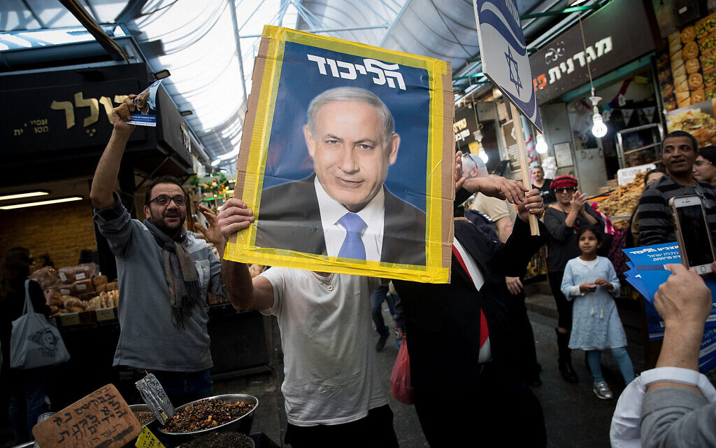 Un partisan du Likud tient une affiche de campagne montrant le Premier ministre Benjamin Netanyahu sur le marché Mahane Yehuda de Jérusalem, le 7 avril 2019 (Crédit : Yonatan Sindel/Flash90) Un partisan du Likud tient une affiche de campagne montrant le Premier ministre Benjamin Netanyahu sur le marché Mahane Yehuda de Jérusalem, le 7 avril 2019 (Crédit : Yonatan Sindel/Flash90)