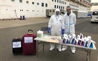 Des responsables portant des vêtements de protection attendent que les passagers israéliens quittent le navire de croisière Diamond Princess où ils ont passé deux semaines en quarantaine en raison d'une épidémie de coronavirus à bord, le 20 février 2020. (Crédit : Ambassade d'Israël à Tokyo)