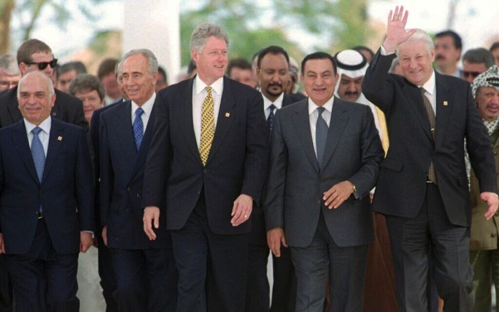 Sur cette photo du 13 mars 1996, le président russe Boris Eltsine fait signe de la main alors que lui et (de gauche à droite) le roi Hussein de Jordanie, le Premier ministre israélien Shimon Pérès, le président américain Bill Clinton, le président égyptien Hosni Moubarak et, à l'extrême droite, le chef de l'OLP Yasser Arafat se dirigent vers la photo de groupe à la fin de leur sommet d'une journée des "bâtisseurs de la paix" à Charm el-Cheikh, en Égypte. (AP Photo/Jerome Delay, File)