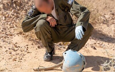 Un aviateur inspecte le casque d'un pilote israélien mort dans un accident d'avion dans le sud d'Israël en 1984, dans le désert de Paran en février 2020. (Crédit : armée israélienne) Un aviateur inspecte le casque d'un pilote israélien mort dans un accident d'avion dans le sud d'Israël en 1984, dans le désert de Paran en février 2020. (Crédit : armée israélienne)