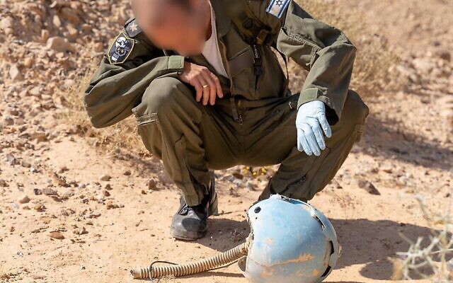 Un aviateur inspecte le casque d'un pilote israélien mort dans un accident d'avion dans le sud d'Israël en 1984, dans le désert de Paran en février 2020. (Crédit : armée israélienne)