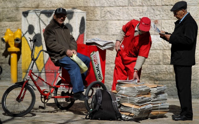Un distributeur du journal Israel Hayom offre des copies gratuites aux passants à Jérusalem (Crédit :  flash90)