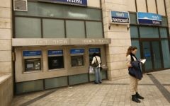 Des Israéliens retirent de l'argent aux distributeurs de la banque Leumi à Jérusalem (Crédit : Miriam Alster/Flash90)