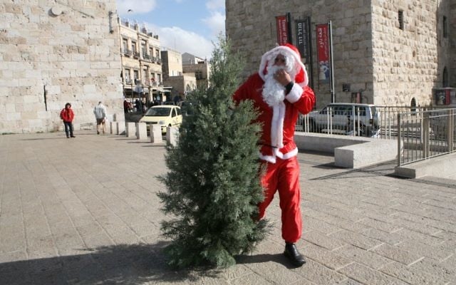 Un homme habillé en Père Noël avec un sapin de Noël, porte de Jaffa, devant la Vieille Ville de Jérusalem, en décembre 2008. Illustration. (Crédit : Yossi Zamir/Flash90) Un homme habillé en Père Noël avec un sapin de Noël, porte de Jaffa, devant la Vieille Ville de Jérusalem, en décembre 2008. Illustration. (Crédit : Yossi Zamir/Flash90)