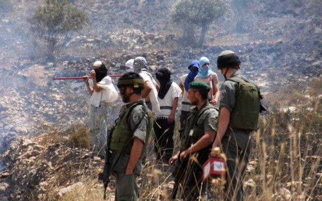 Des résidents masqués d'implantations se tiennent à côté de soldats de Tsahal en Cisjordanie (Crédit photo: Wagdi Ashtiyeh / Flash90) Des résidents masqués d'implantations se tiennent à côté de soldats de Tsahal en Cisjordanie (Crédit photo: Wagdi Ashtiyeh / Flash90)