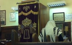 Un homme prie dans une synagogue. Illustration. (Crédit : Aaron Kalman)