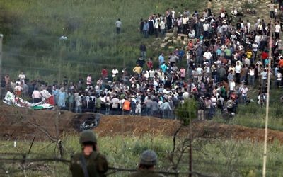 Des manifestants se réunissent le long de la frontière syrienne avec Israël avant de tenter de couper une ligne de fils barbelés et d'entrer sur le plateau du Golan israélien, une photo prise depuis le village druze de  Majdal Shams, 
 le 5 juin 2011 (Crédit : Flash90)
