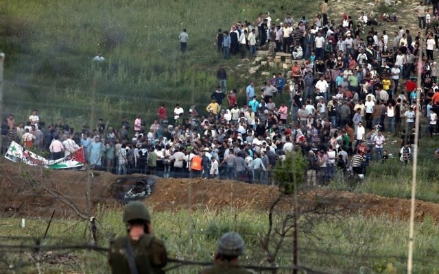 Des manifestants se réunissent le long de la frontière syrienne avec Israël avant de tenter de couper une ligne de fils barbelés et d'entrer sur le plateau du Golan israélien, une photo prise depuis le village druze de Majdal Shams,
le 5 juin 2011 (Crédit : Flash90) Des manifestants se réunissent le long de la frontière syrienne avec Israël avant de tenter de couper une ligne de fils barbelés et d'entrer sur le plateau du Golan israélien, une photo prise depuis le village druze de Majdal Shams,
le 5 juin 2011 (Crédit : Flash90)